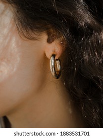 Side view of a woman's face wearing a gold hoop earing.
