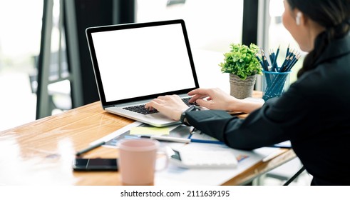 Side View Woman's Using Laptop Computer At Home Office With Cropped Shot. Blank Screen Laptop For Product Display.