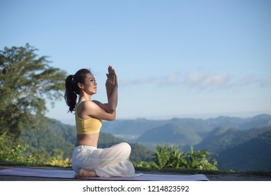 Side view of women practicing yoga. sitting in eagle pose. Anusara Yoga. beautiful landscape on morning with mist on mountain peaks on natural view, concept for exercising, health care