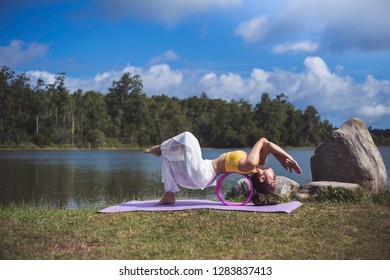 Side view of women practicing yoga. in eagle pose with yoga wheel. Anusara Yoga. on a grass background at parks on natural view, concept for exercising, health care