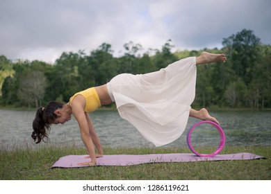 Side view of women practicing yoga. chakrasana wheel pose  with yoga wheel. on a grass background at parks on natural view, concept for exercising, health care