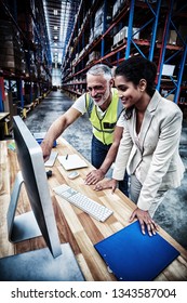 Side View Of Worker Team Is Looking A Computer And Smiling In A Warehouse