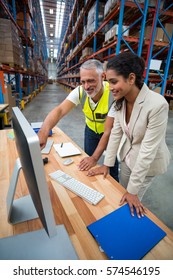 Side View Of Worker Team Is Looking A Computer And Smiling In A Warehouse