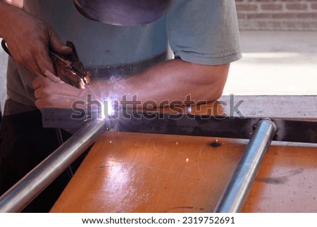 Side view of worker welding. A young man with welding mask and w