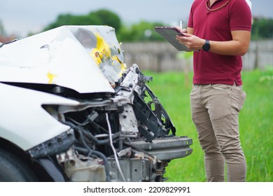 Side view of writing on tablet while insurance agent examining car after accident - Shutterstock ID 2209829991