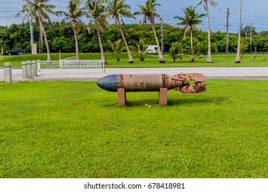 Side view of WWII torpedo in a public park in Guam with palm trees in the background