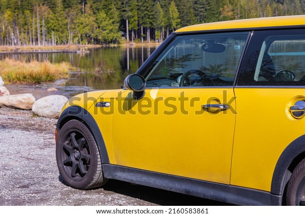 Side view of\
a Yellow Mini Cooper S car on natural background. Yellow Mini\
Cooper parked in the park-April 27,2022-Whonnock Lake BC,\
Canada-Travel photo, nobody, selective\
focus