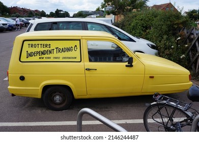 Side view of Yellow Reliant Robin three wheeler van in a parking lot with Trotter`s Independent trading on the side. Sheringham Norfolk UK. Aug 2021