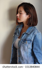 Side View Young Adult Asian Woman, Red Lip And Short Hair In Blue Jean With Beauty Face And Looking Away With White Wall