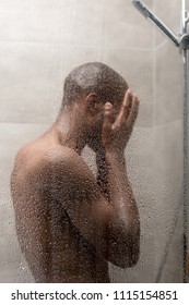 side view of young african american man washing body in shower  