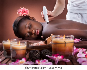 Side View Of Young African American Woman Undergoing Microdermabrasion Therapy At Beauty Spa