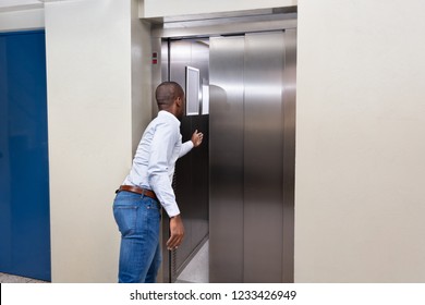 Side View Of A Young African Man Stopping Elevator Door With His Hand