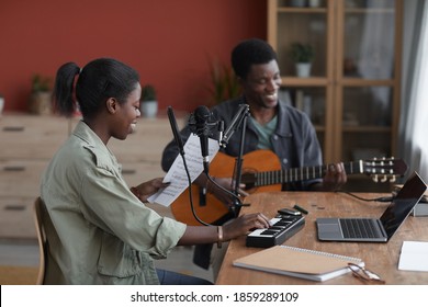 Side view at young African-American couple composing music together in home recording studio, copy space - Powered by Shutterstock