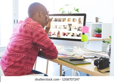 Side view of young African-American graphic designer sitting upset at desk in office  - Powered by Shutterstock