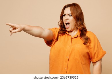 Side view young angry sad ginger chubby overweight woman wear orange shirt casual clothes point index finger aside isolated on plain pastel light beige background studio portrait. Lifestyle concept - Shutterstock ID 2363739525