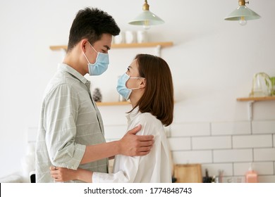 Side View Of Young Asian Couple Wearing Mask Holding And Looking At Each Other