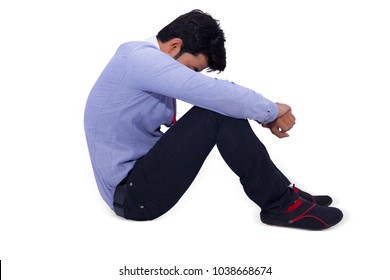 Side view of a young Asian formal man sitting disappointed on floor and looking down between legs. Isolated on white Background
