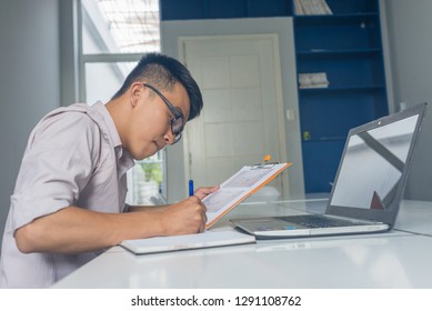 Side View Of Young Asian Office Man Writing Note In The Business Office