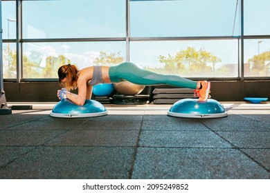 Side View Young Attractive Female Athlete In Activewear Doing Push-ups On Double Bosu Ball During Workout At Gym. Workout, Physical Exercise For Core And Balance.