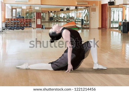 Side view of young ballerina wearing black tutu while dancing in the ballet class