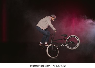 side view of young bmx cyclist performing stunt with bike in smoke - Powered by Shutterstock