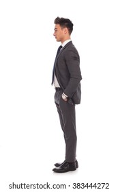 Side View Of A Young Business Man Standing In Line With Hands In His Pockets