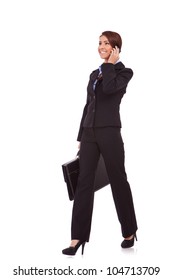 Side View Of A Young Business Woman Talking On The Phone And Holding A Brief Case While Walking On White Background