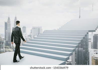 Side view of young businessman climbing abstract stairs on bright Kuala Lumpur city background. Career development and ascend concept 