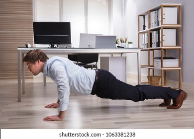 Side View Of A Young Businessman Doing Push Up In Office - Powered by Shutterstock