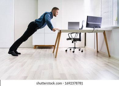 Side View Of A Young Businessman Doing Push Up On Office Desk - Powered by Shutterstock