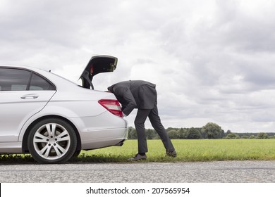 Side View Of Young Businessman Looking In Trunk Of Car At Countryside