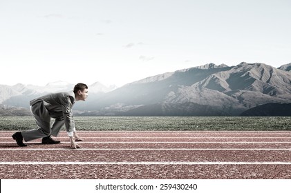 Side view of young businessman in start position on track - Powered by Shutterstock