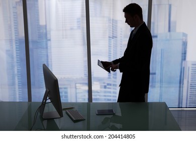 Side view of young businessman using digital tablet at desk in office - Shutterstock ID 204414805
