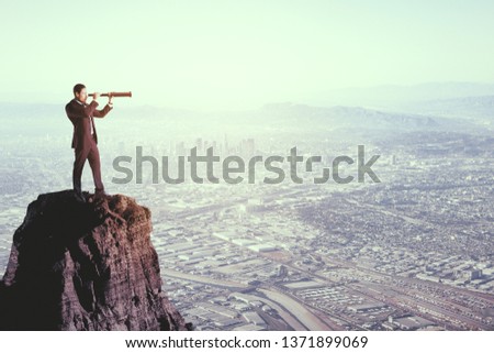 Side view of young businessman using telescope on hill. Blurry city background. Research and vision concept 
