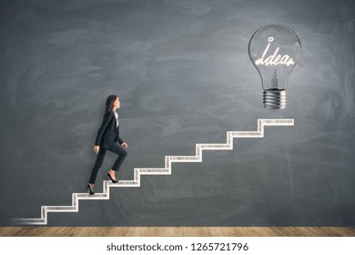 Side view young businesswoman climbing abstract drawn stairs and idea lamp chalkboard background  Solution   innovation concept 