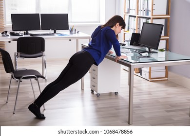 Side View Of A Young Businesswoman Doing Push Up On Office Desk