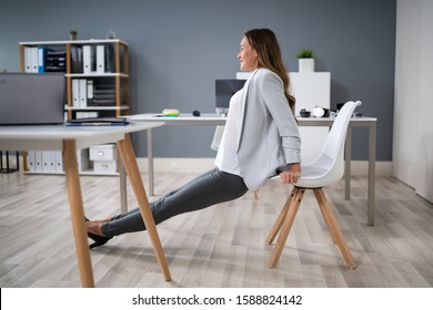 Side View Of A Young Businesswoman Doing Triceps Dips In Office