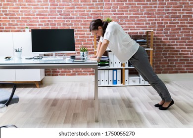 Side View Of A Young Businesswoman Doing Push Up On Office Desk