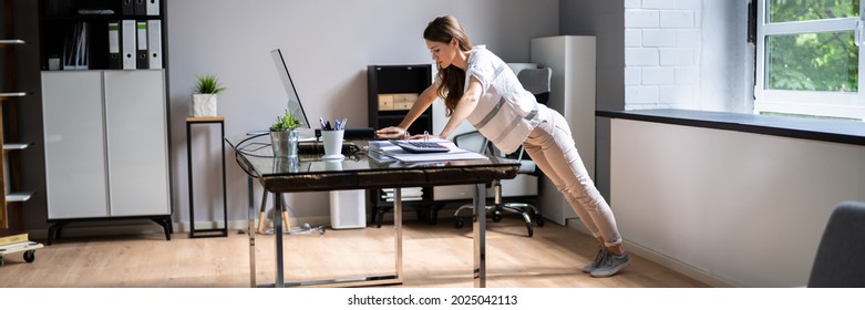 Side View Of A Young Businesswoman Doing Push Up On Office Desk