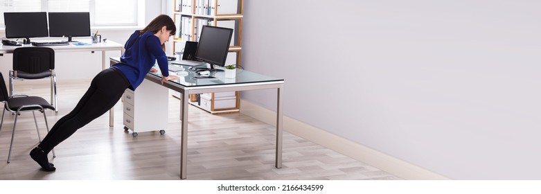 Side View Of A Young Businesswoman Doing Push Up On Office Desk