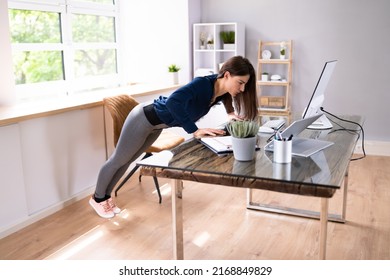 Side View Of A Young Businesswoman Doing Push Up On Office Desk - Powered by Shutterstock