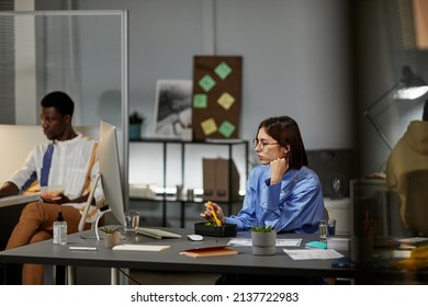 Side View At Young Businesswoman Eating Takeout Dinner At Desk While Working In Office Late, Copy Space