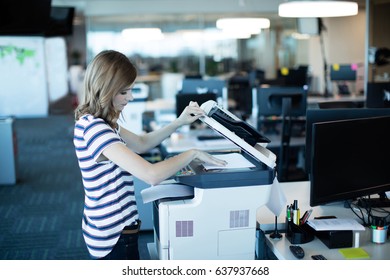 Side View Of Young Businesswoman Using Copy Machine In Office