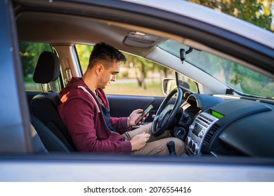 Side View Of Young Caucasian Man Checking Mobile Phone For Messages Or Navigation App For Destination While Sitting In Car Driving Or Parking Real People Travel Concept