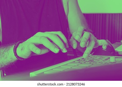 side view of young caucasian man making beat on a midi controller, producing and composing electronic music and commercial urban music.