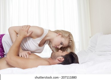 Side View Of Young Couple Cuddling In Bed