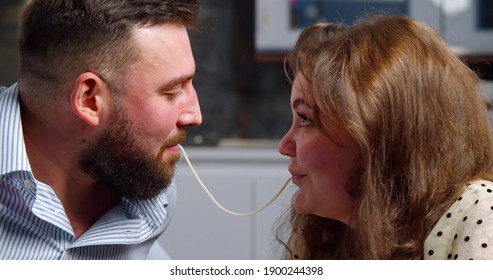 Side View Of Young Couple Eating Pasta And Kissing Enjoying Romantic Dinner. Close Up Of Happy Man And Woman In Love Eating Spaghetti And Kissing In Kitchen At Home