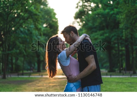 side view of young couple hugging each other and having fun on meadow 
