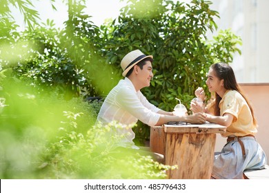 Side view of young couple sitting in outdoors cafe when having date - Powered by Shutterstock