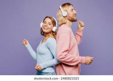 Side view young couple two friends family man woman wear pink blue casual clothes together listen to music in headphones stand back to back isolated on pastel plain purple background studio portrait - Powered by Shutterstock